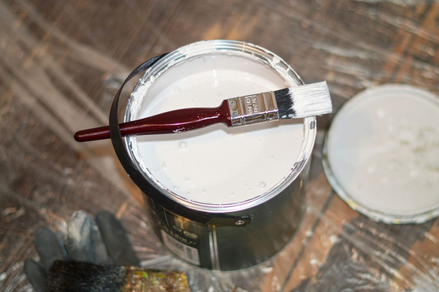 Paint brush resting on an open can of white paint