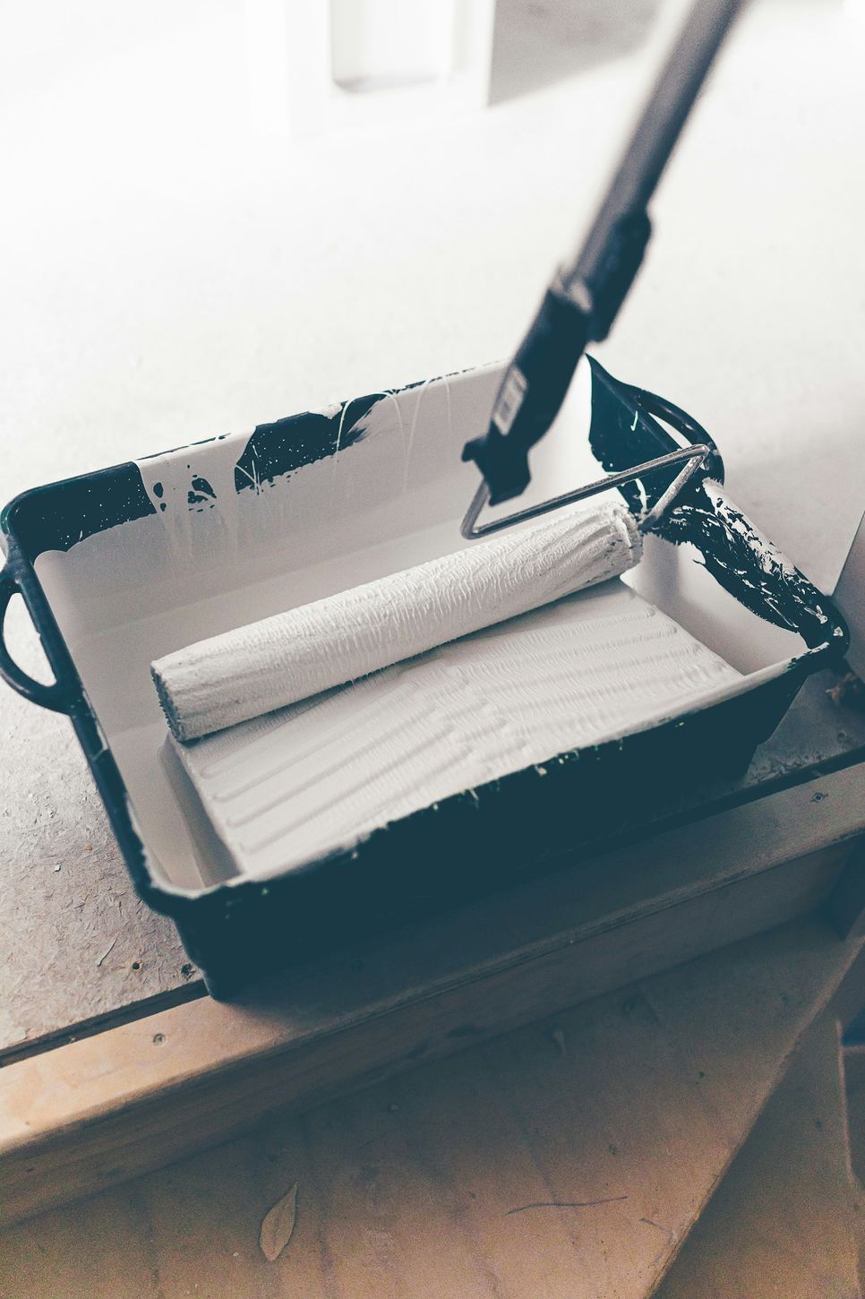 Paint roller in a tray filled with white paint