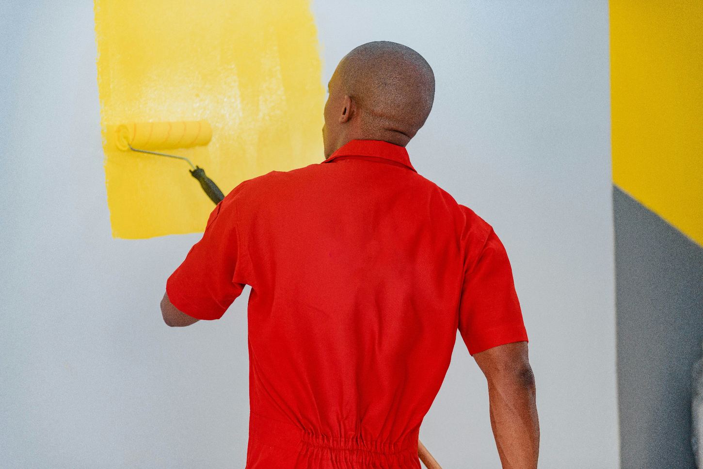 Painter applying a bright yellow coat with a paint roller